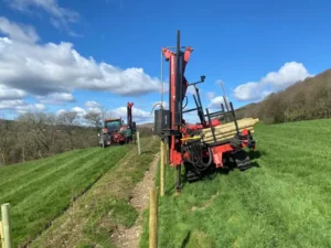 Red tractor with a post laying machine for use with wire fencing